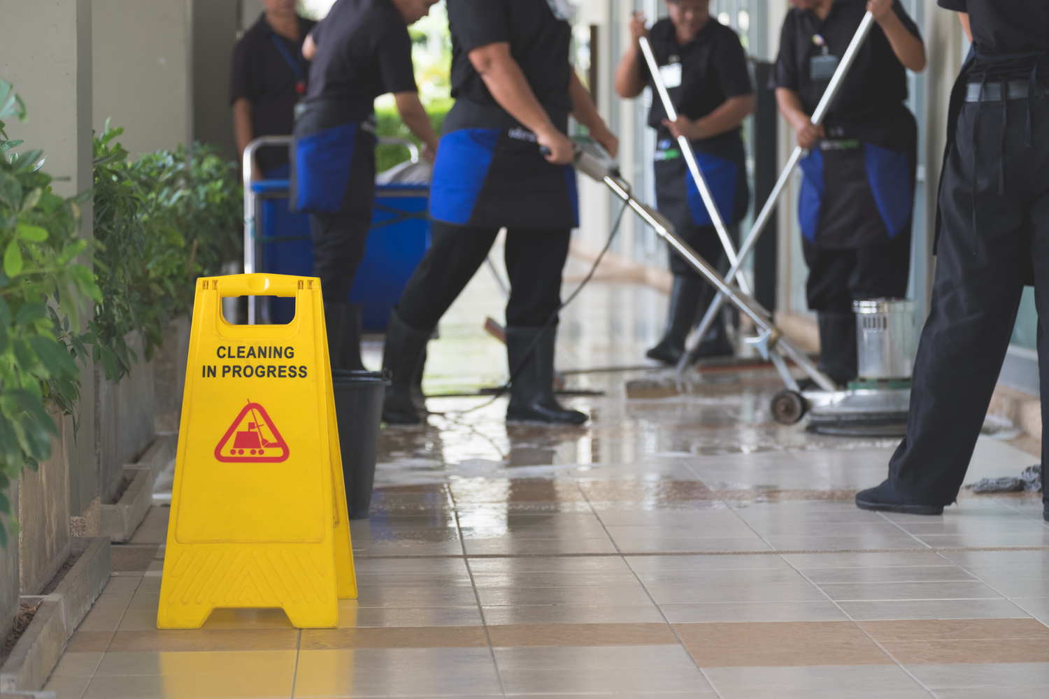 Cropped image of group of woman in protective gloves using a flat wet-mop and machine while cleaning floor