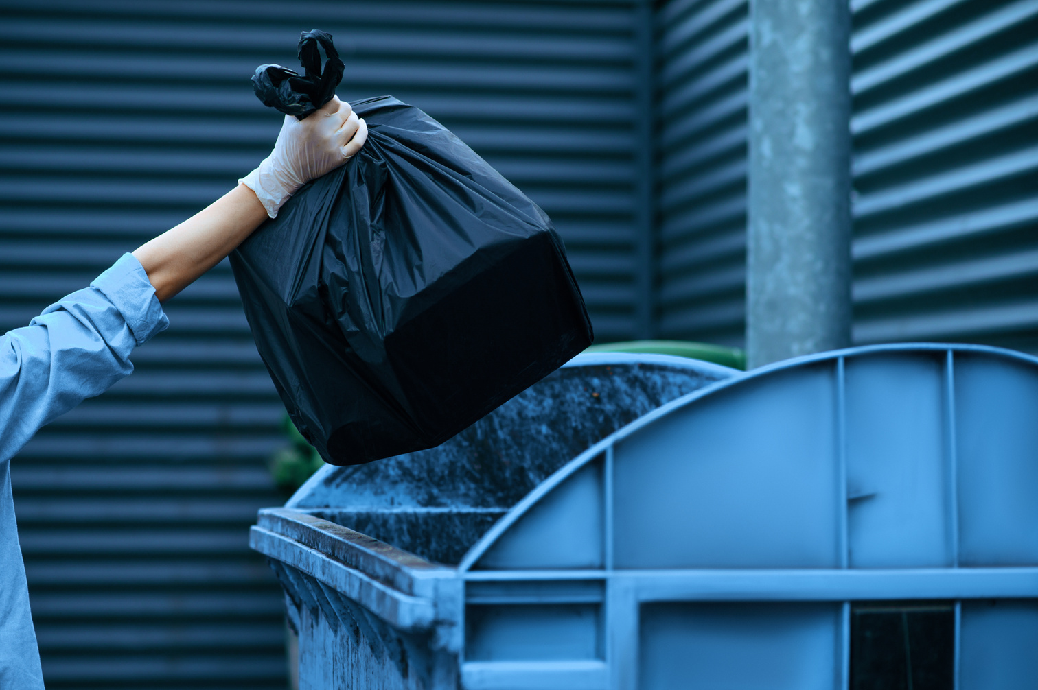 Volunteer puts plastic trash bag into the bin outdoors, volunteering. People cleans city streets, ecological restoration, garbage collection and recycling, ecology care, environment cleaning